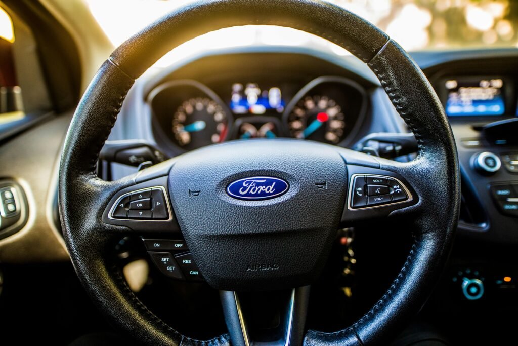 Detailed view of a car steering wheel and dashboard with illuminated controls.